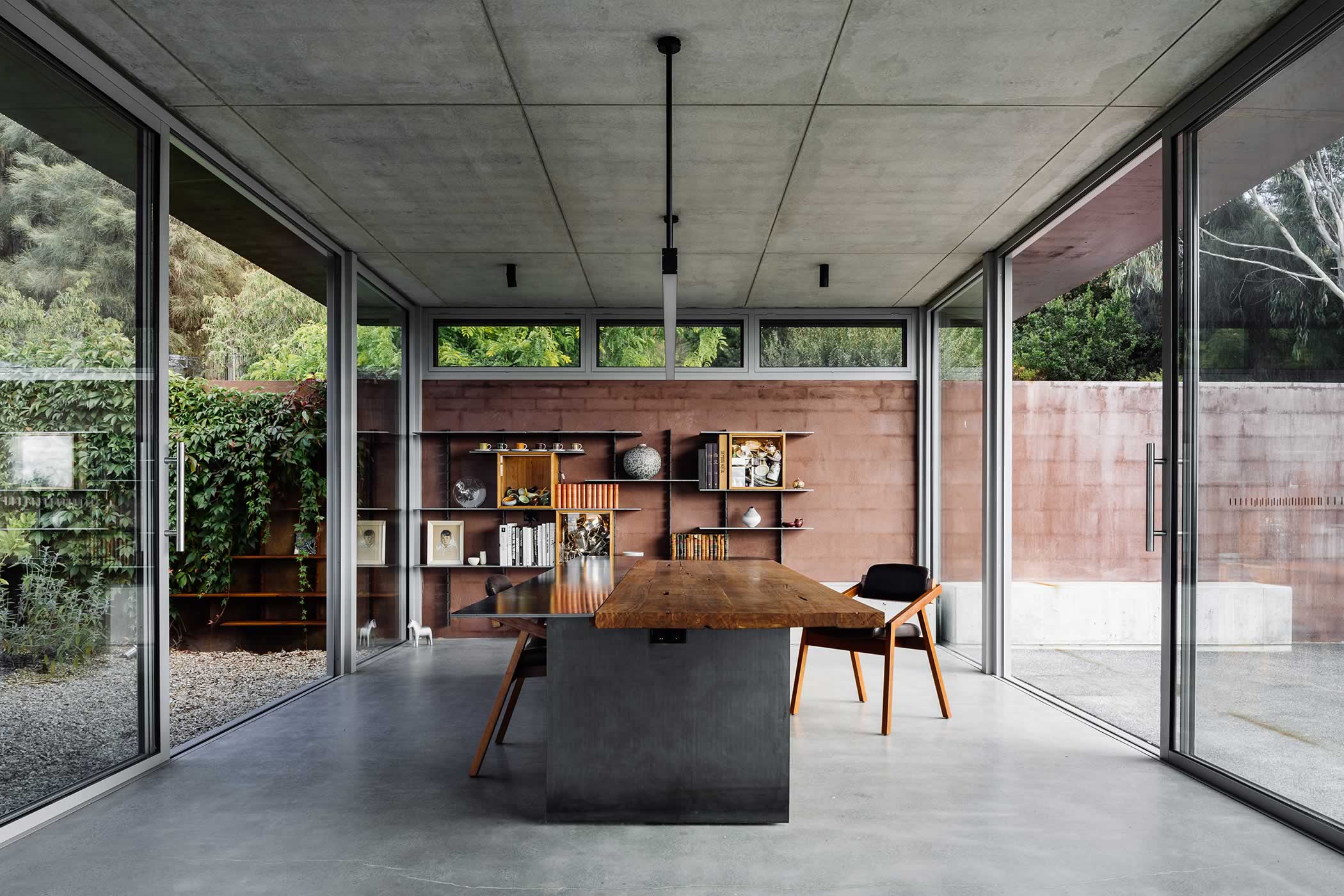 Residential extension, Kettering, Tasmania: Off-shutter concrete “floats” above a light expansive studio below. Glazing brings the outside in and inside out. The plan closes the courtyard and is orientated for natural warmth and light. Photo by Adam Gibson.