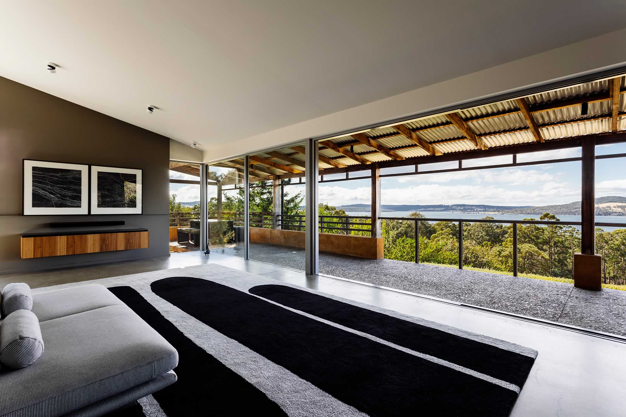 Residential extension, Kettering, Tasmania: The extended living space is gloriously fully opened to the natural setting and is dramatic changing light, colour and atmospheric conditions but retains façade integrity. Photo by Adam Gibson.