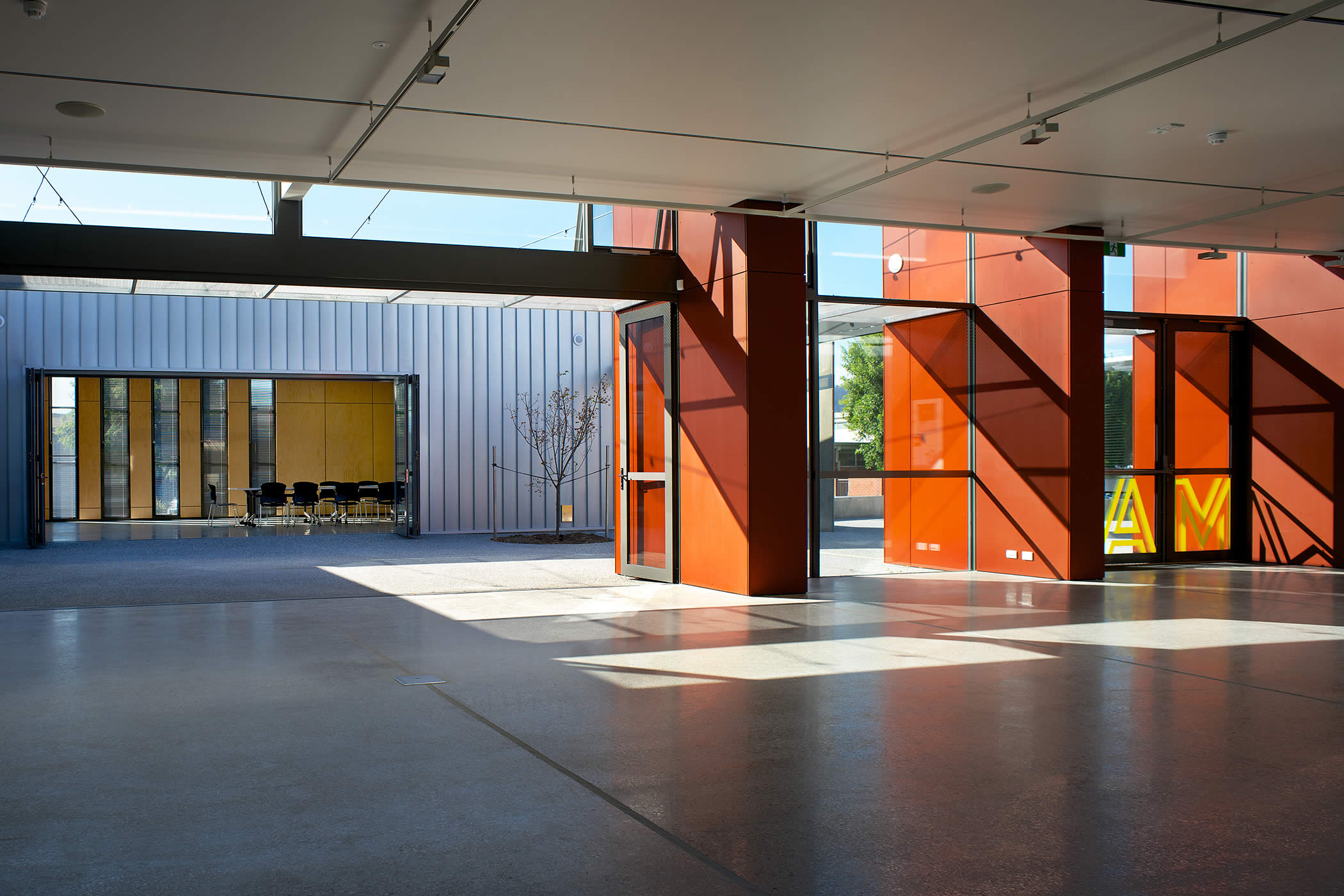 Moonah Arts Centre (MAC), City of Glenorchy, Tasmania: Flexible spaces form large interlinking areas or separate specialized zones and glazed bi-fold doors open foyer and workshop to shared external courtyard space. Photo by Ray Joyce.