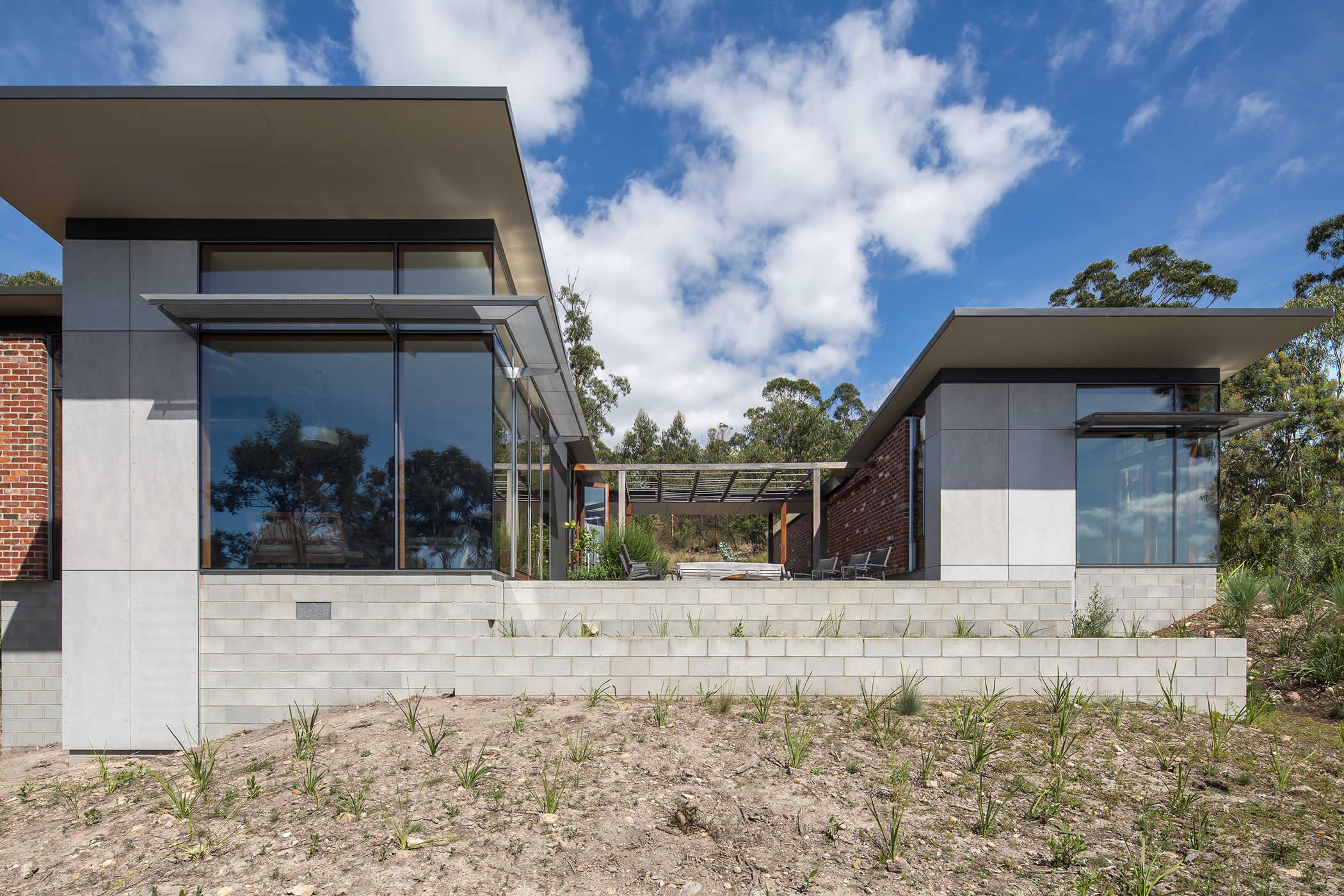 Sandy Bay, Tasmania: External courtyards link the two pavilions. They create inside–outside space, shelter from wind and weather, frame spectacular water views, and define the limits of encroachment in the bush. Photo by Thomas Ryan.