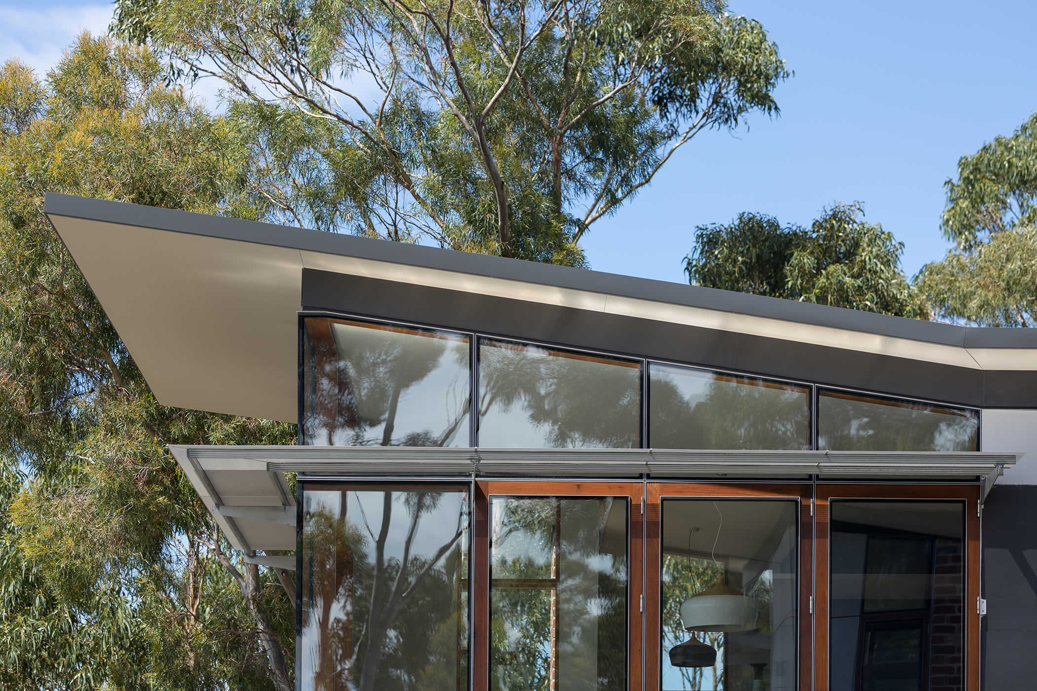 Sandy Bay, Tasmania: Passive solar features combine a soaring roof overhang, eaves and well placed sun-shades with double glazing, insulation, thermal mass and hydronic heating for year round thermal comfort. Photo by Thomas Ryan.