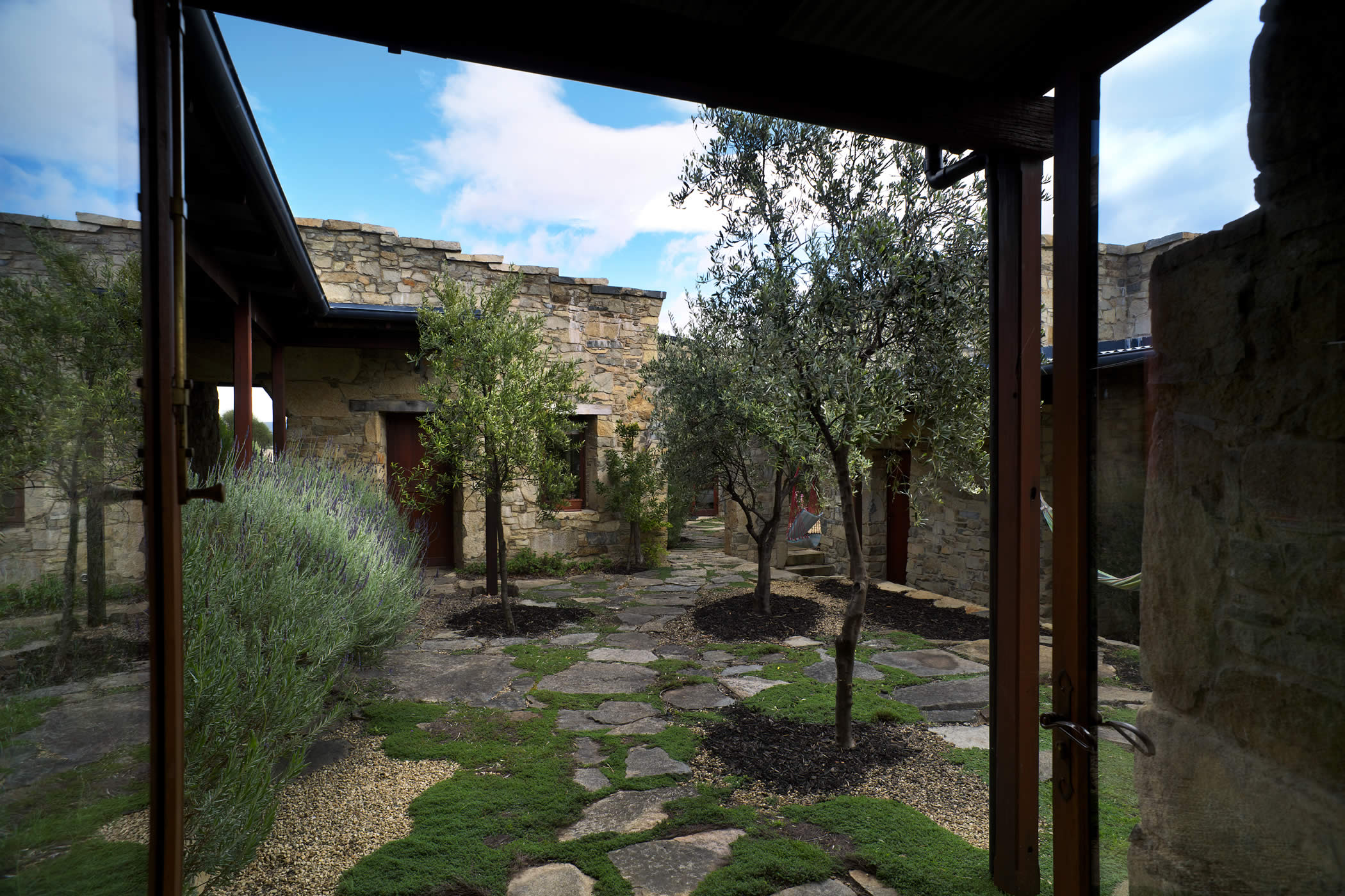 Thalia Haven, East Coast Tasmania: An olive treed and thyme planted stone-paved courtyard links separate stone pavilions and gives shelter from the wind. Photo by Ray Joyce.