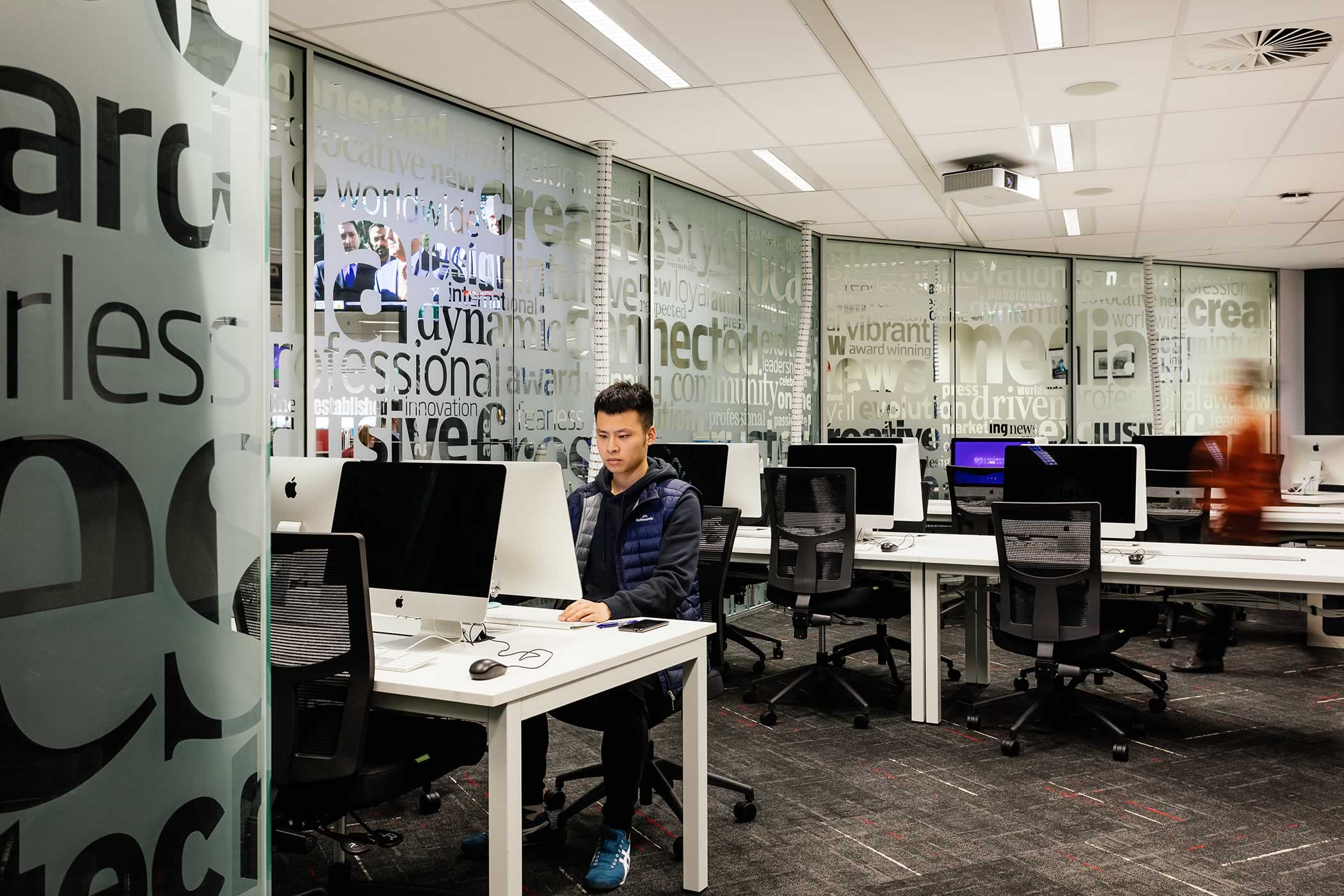 The Media School – University of Tasmania: The student hub and Mac laboratory share The Mercury’s existing glazed graphics feature wall benefitting from the light and atmosphere it presents. Photo by Adam Gibson.