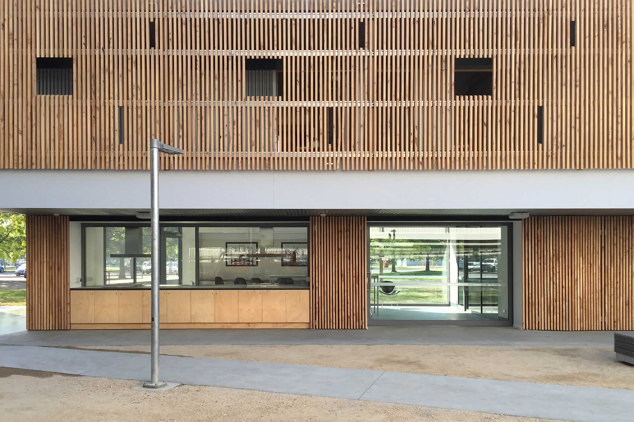 UTAS Inveresk Student Residences, Tasmania: Macrocarpa timber screens frame the view through the ground floor laundry common room with attention to visual transparency for safety in the public realm of the site. Photo by James Morrison.